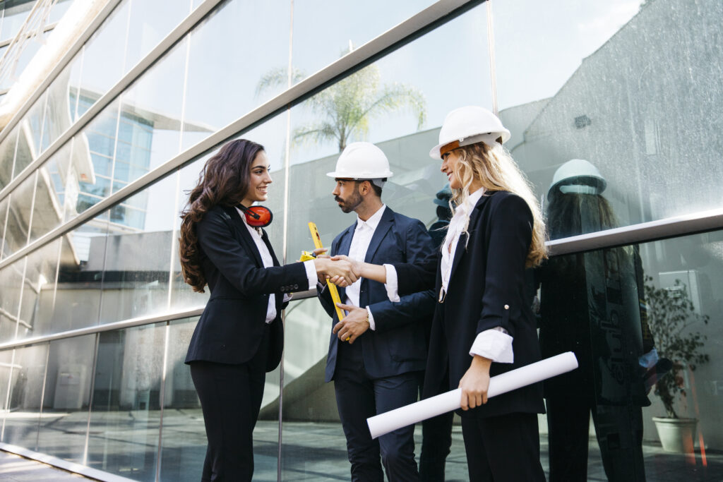 A satisfied client shaking hands with commercial construction company representative in front of a newly completed building.