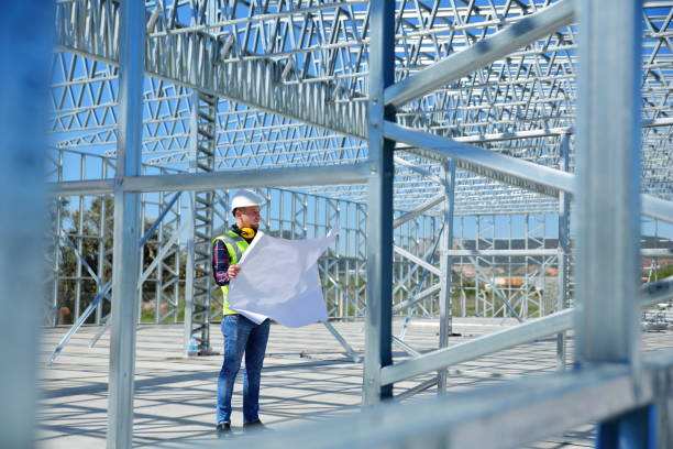 Steel frame building construction with a worker checking plans