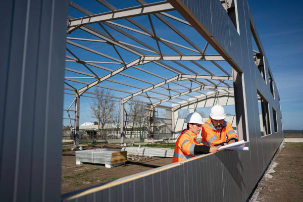 Two contractors discussing plans during steel frame assembly