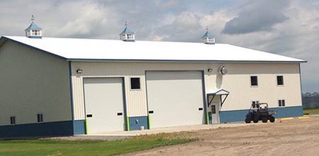 Completed farm shop building with large garage doors and a white roof