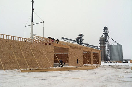 Wooden framework for a farm maintenance building with crane operation