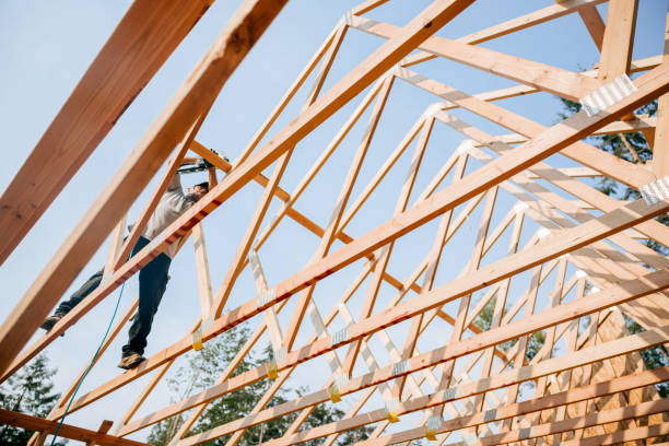 Worker installing trusses during post frame pole barn construction
