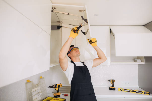 Worker adjusting upper kitchen cabinets during remodeling project