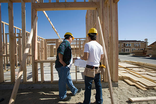 Two spec home builders reviewing construction plans on a building site