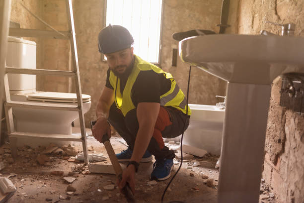 Contractor renovating bathroom floor during addition project