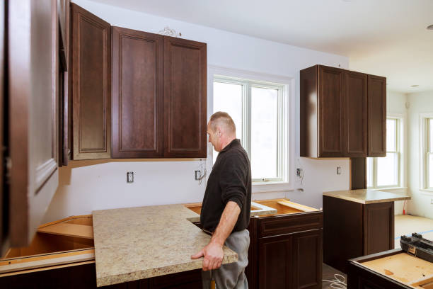 Worker installing laminate countertop on dark wood kitchen base cabinets