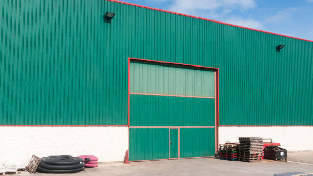 Green Agricultural building with large door and storage equipment