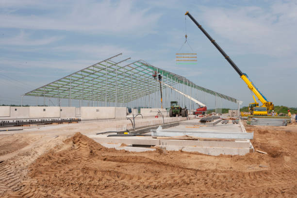 Workers building metal livestock housing with crane assistance