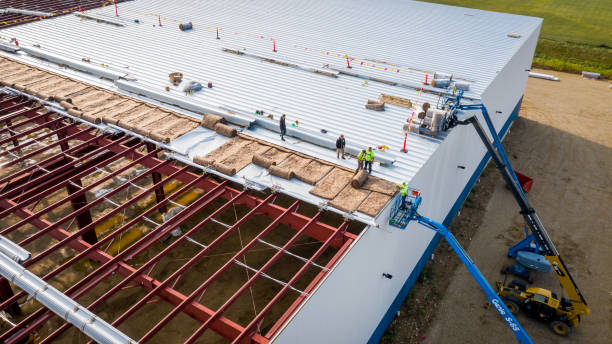 Workers on a lift adding roof panels to poultry barn construction
