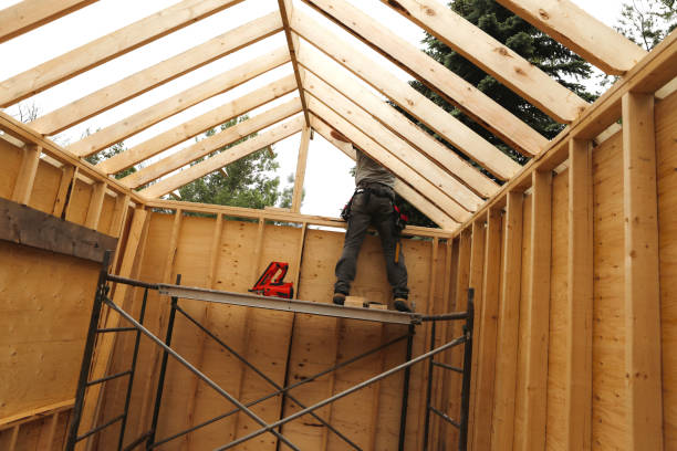 Worker constructing a horse barn roof structure with scaffolding