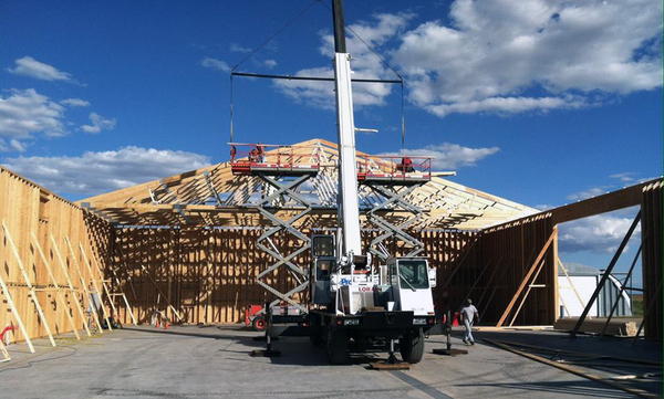 Shed building construction in progress with crane lifting roof trusses