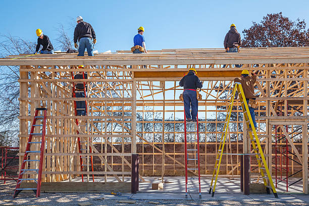 Workers building a shed with wood framing and ladders on the construction site