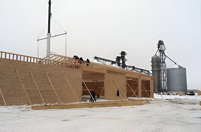 Skilled workers installing trusses and wall panels on a new pole barn